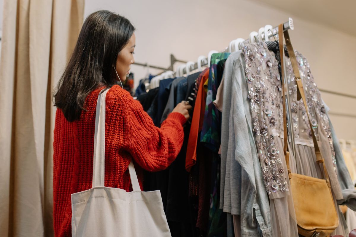 Kvinna letar bland kläder på en klädstång i en second hand-butik